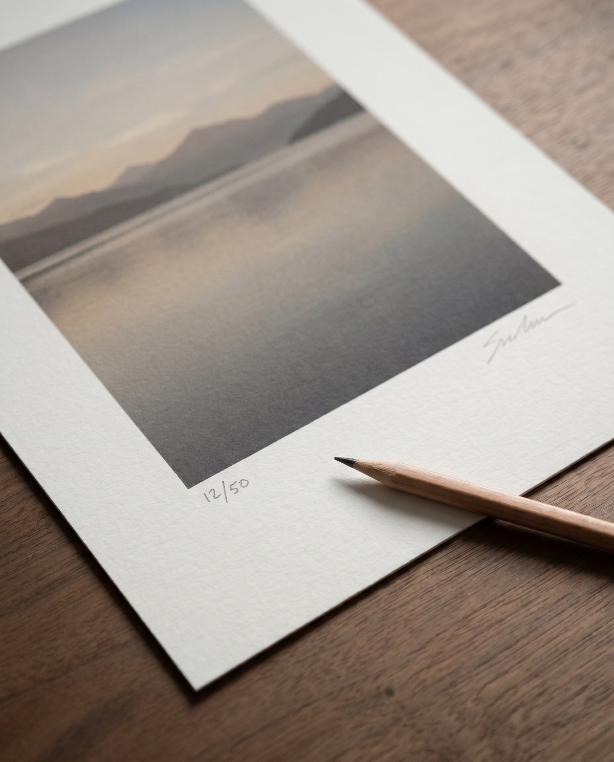Signerad och numrerad giclée edition-print på matt valnötsbord, blyertspenna vilande över nedre kanten, edition 12/50